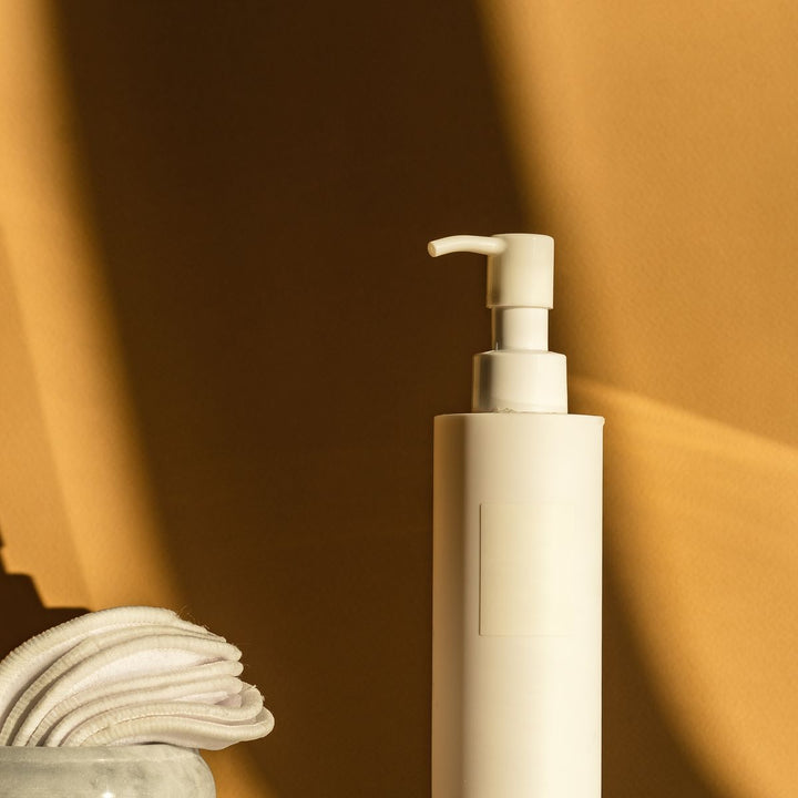 Body care pump bottle and cotton pads in warm neutral light